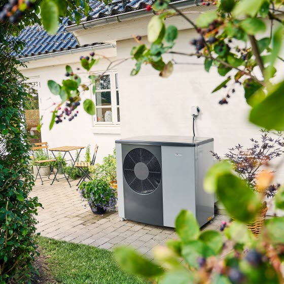 Varmepumpe står på terrassen foran et hvidt hus