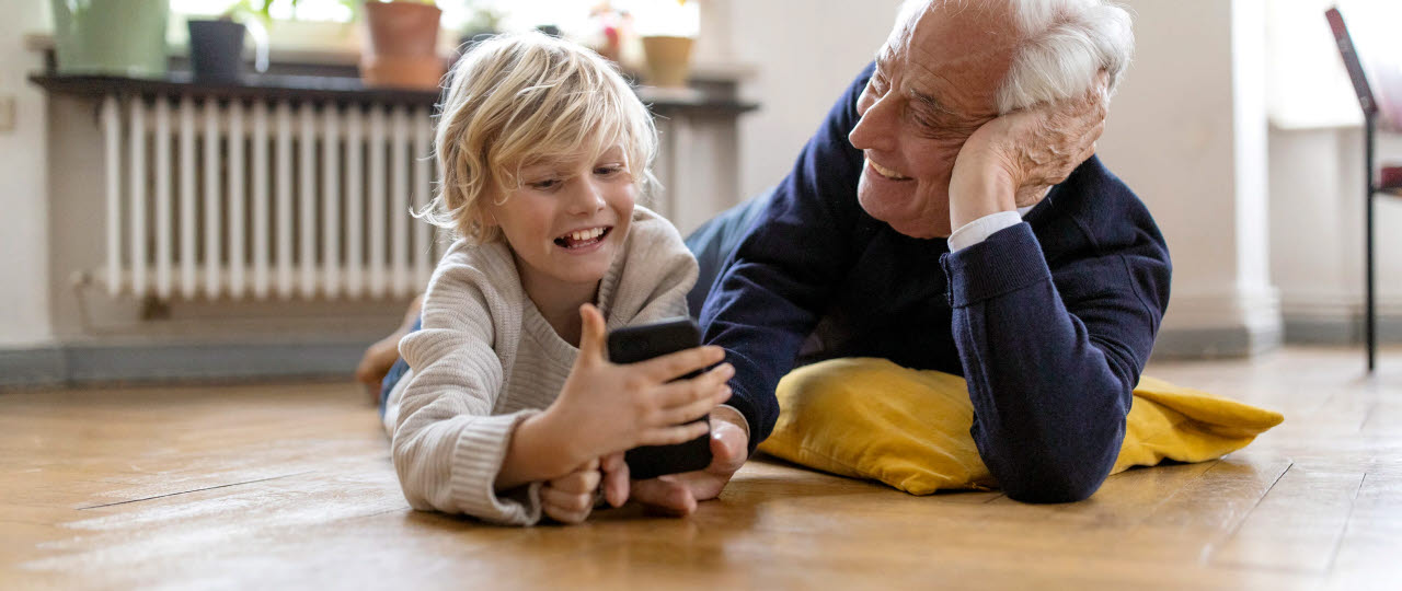 Ældre mand leger med barnebarn på gulvet