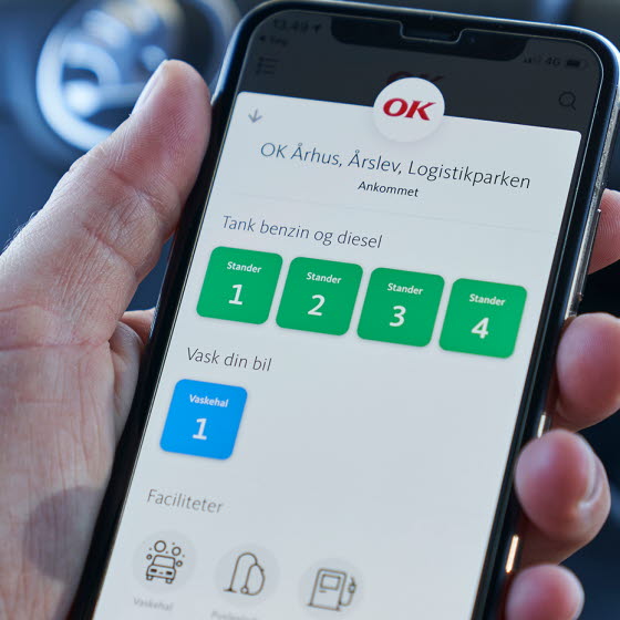 Hånd holder mobil med OK's app